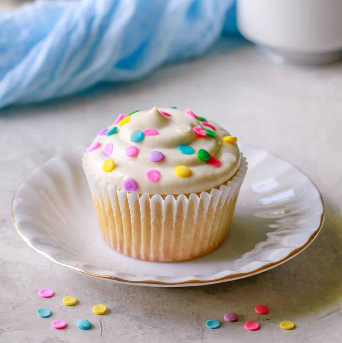 a close-up shot of a vanilla protein cupcake with frosting and sprinkles