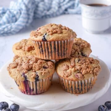 oat flour blueberry muffins with crumb topping on a white serving plate