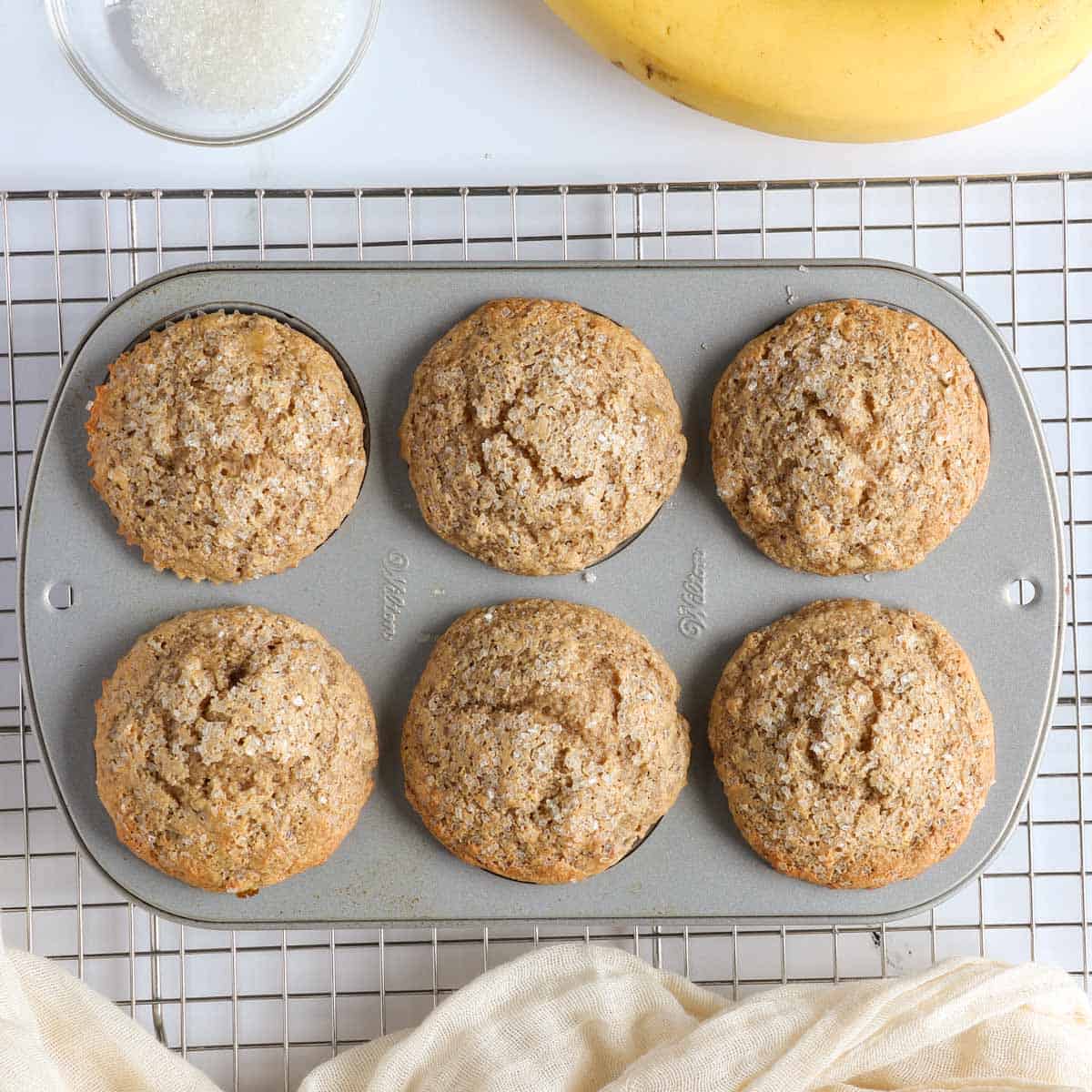 Freshly baked oat flour banana muffins with tall domed tops in a muffin pan