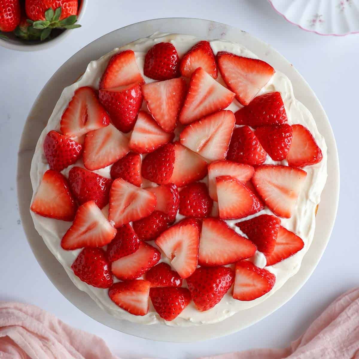Top-down view of healthy strawberry shortcake cake topped with maple yogurt cream and fresh strawberries
