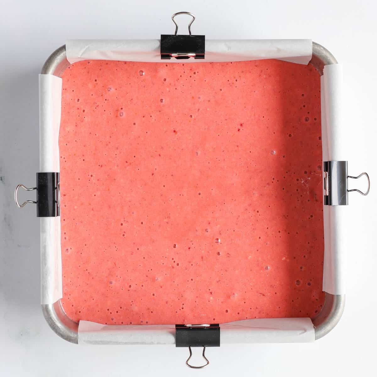 Strawberry protein bar batter in an 8 inch square pan