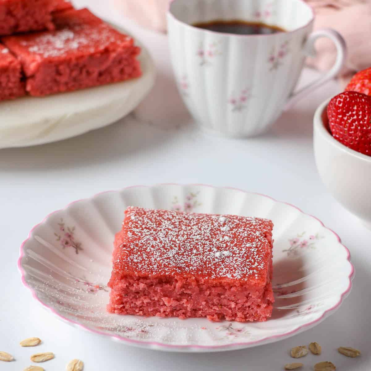 Strawberry protein bar topped with powdered sugar on a white plate with pink trim