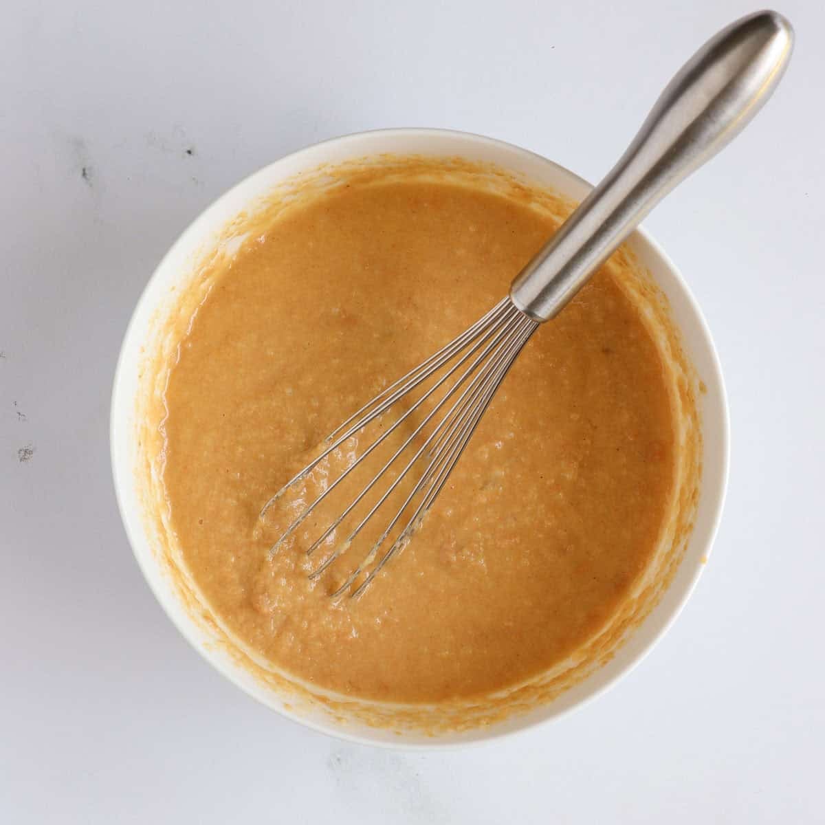 Peanut butter, applesauce, water, egg, and olive oil mixed together in a bowl.