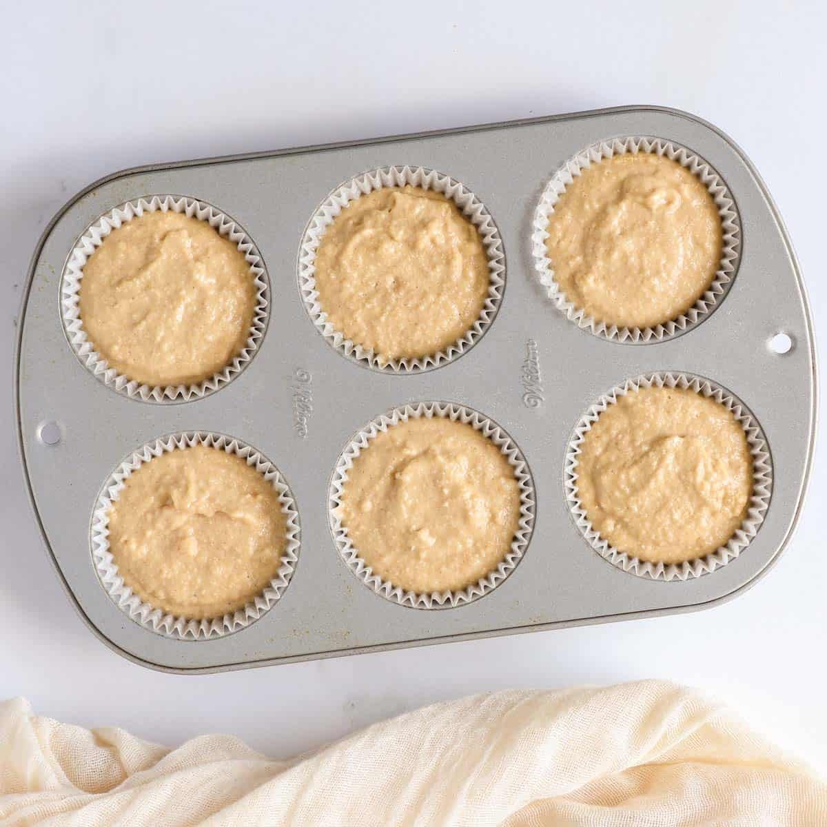 Dog muffin batter divided evenly into a lined muffin pan before baking.