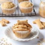 a peanut butter oat dog muffin topped with peanut butter drizzle on a white plate