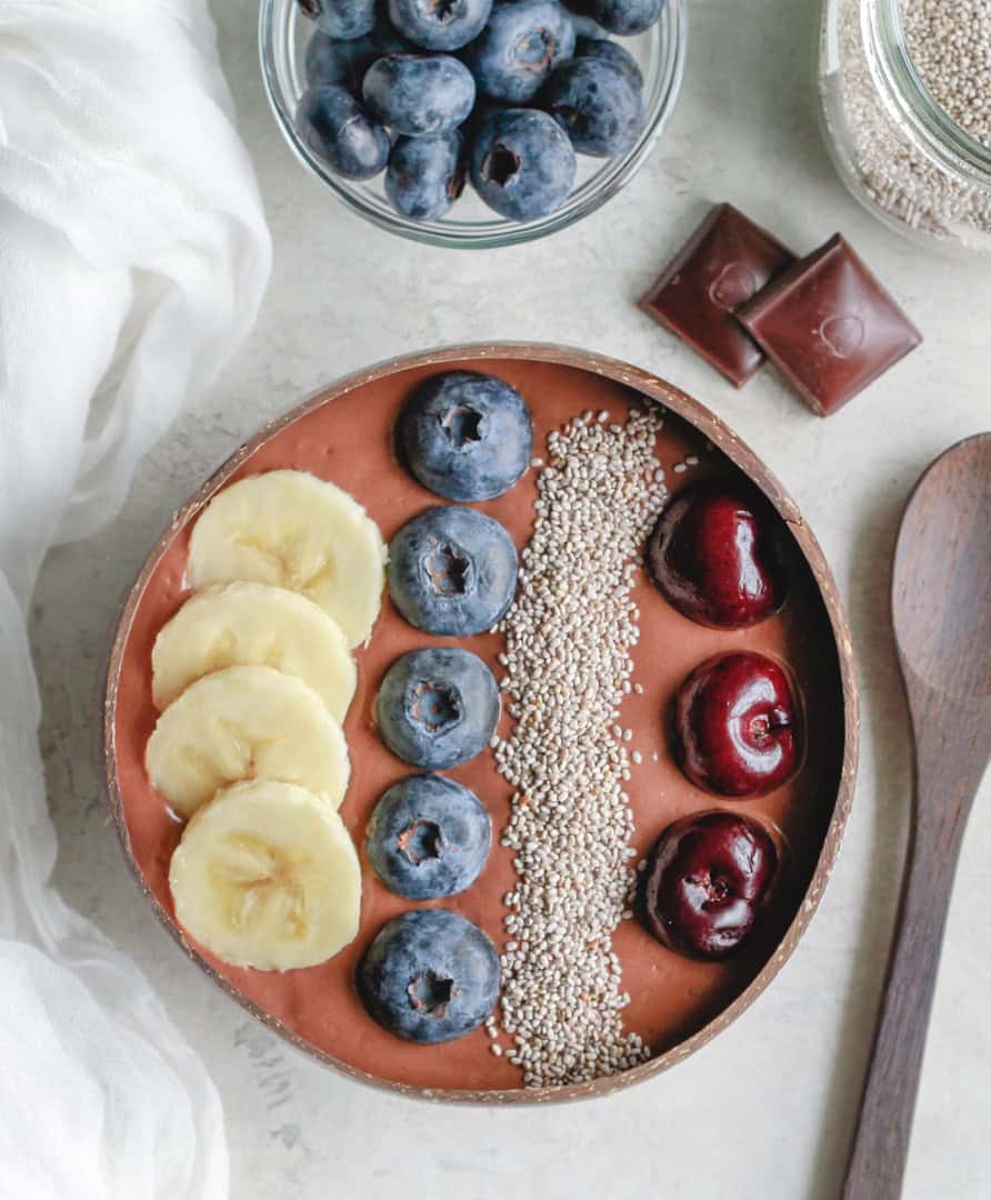 chocolate chia oat pudding topped with bananas, blueberries, cherries, and chia seeds